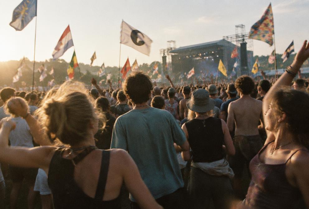 Festival crowd facing an outdoor stage in late-afternoon light